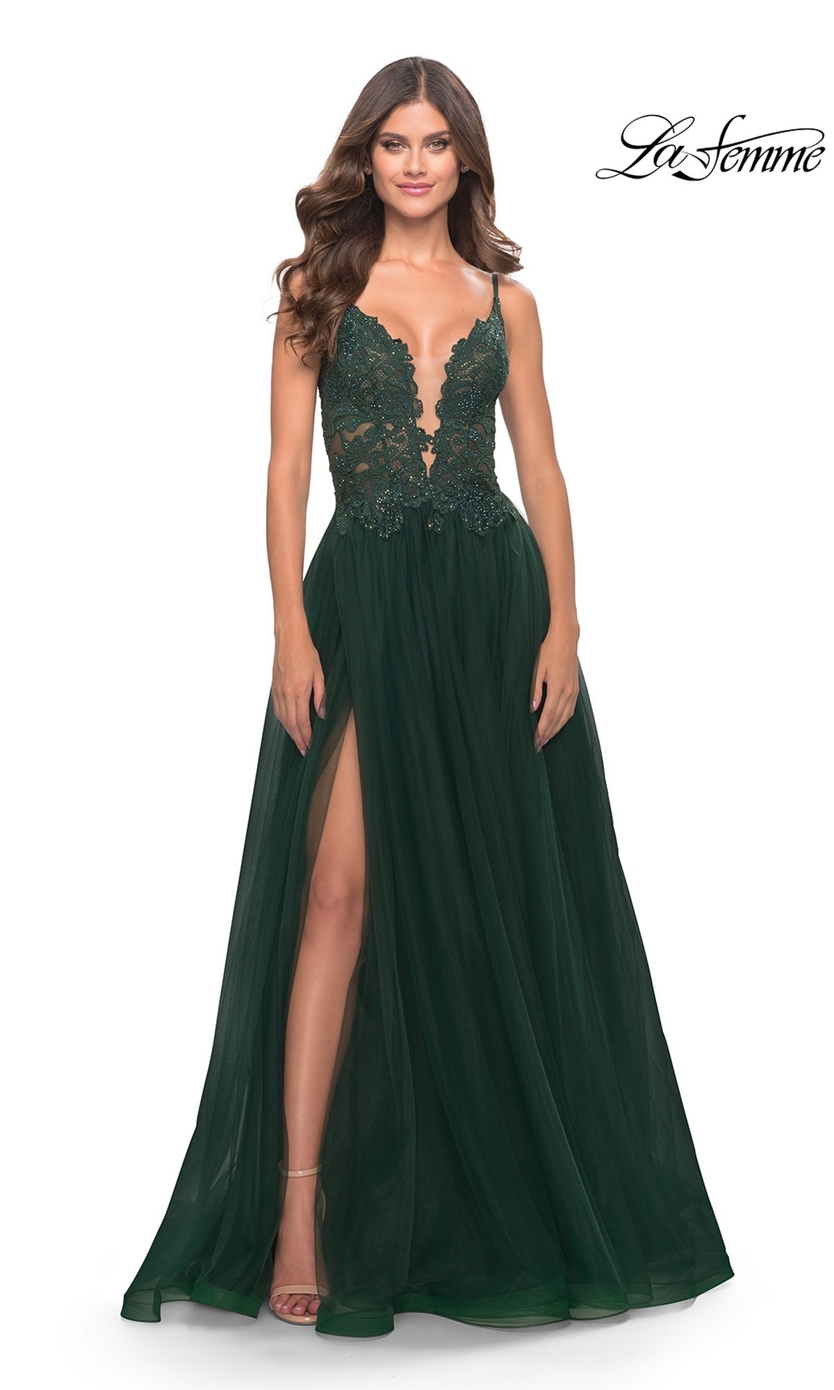 A woman in the La Femme 31507 Lace-Bodice Long Tulle Prom Dress—a dark green, floor-length gown featuring a lace bodice, deep V-neckline, thin straps, high leg slit, and sheer flowing skirt.